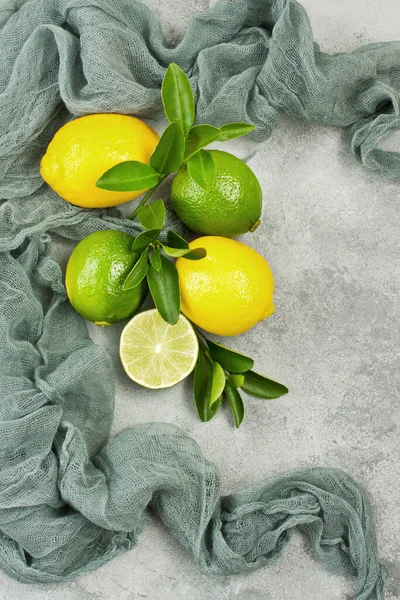 Composition of delicious citrus fruit and green leaves on gray concrete background, top view with copy space