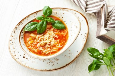 Ahşap masada mevsimlik sebzelerle seramik çorba kasesi, üst manzara. İtalyan gıda konsepti