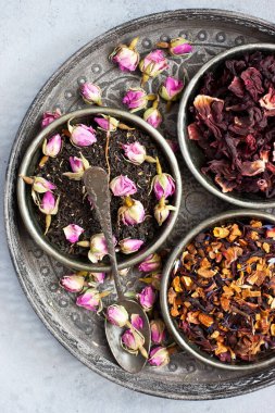 Siyah, yeşil, bitkisel çay yaprakları ve eskimiş kaşık ve çimento renkli gül tomurcukları. Kopyalama alanı olan üst görünüm