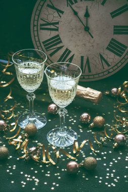 İki bardak köpüklü şampanya, konfetilerin altın süslemesi ve renkli arka planda yılanlar. Şenlikli ya da parti konsepti