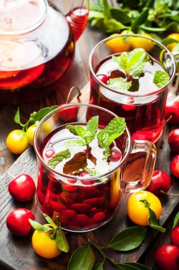 Taze nane yapraklı çay ve cam bardakta narenciye dilimleri, koyu ahşap zemin üzerinde çaydanlık. Meyve suyunu doğal vitaminlerle iyileştiriyorum.