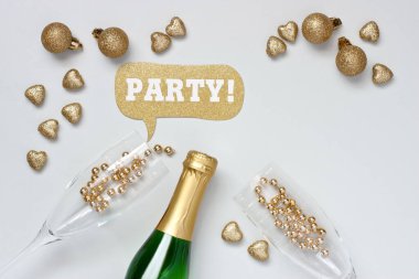 Altın toplar ve kalplerden yılbaşı süslemeleri olan şampanya şişesi ve bardak. Düz yatıyordu 