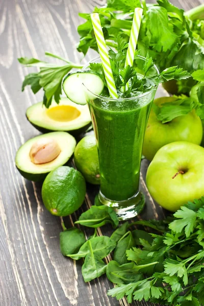 Healthy green smoothie with spinach, lime and apple in glass  on rustic wooden background. Healthy food concept