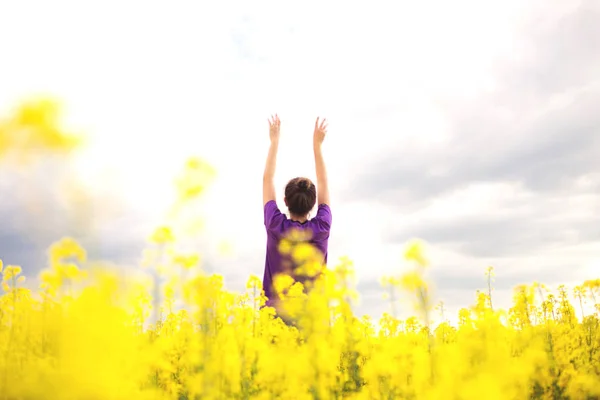 पीले फील्ड फूलों की पृष्ठभूमि पर युवा लड़की . — स्टॉक फ़ोटो, इमेज