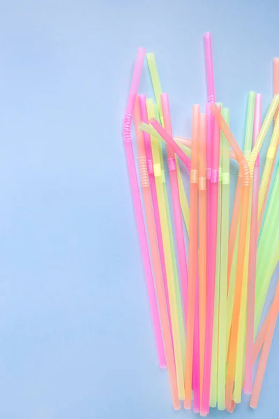 Colourful plastic straws on blue background. Cocktail tubes.