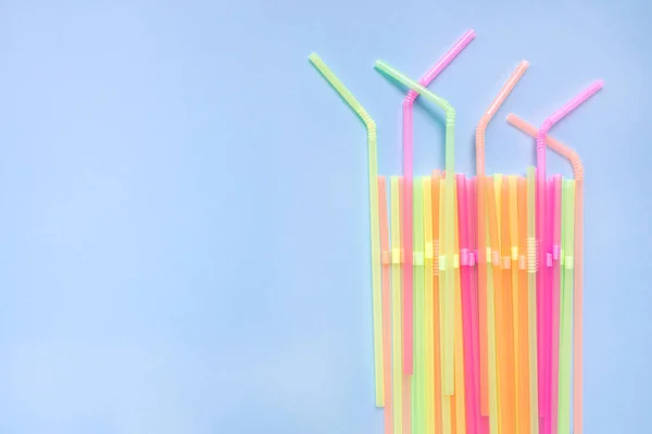 Colourful plastic straws on blue background. Cocktail tubes.