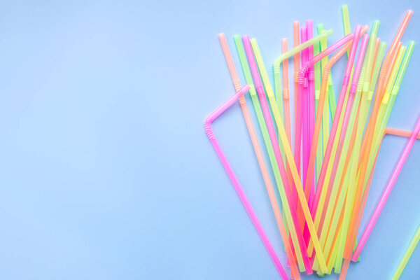 Colourful plastic straws on blue background. Cocktail tubes.