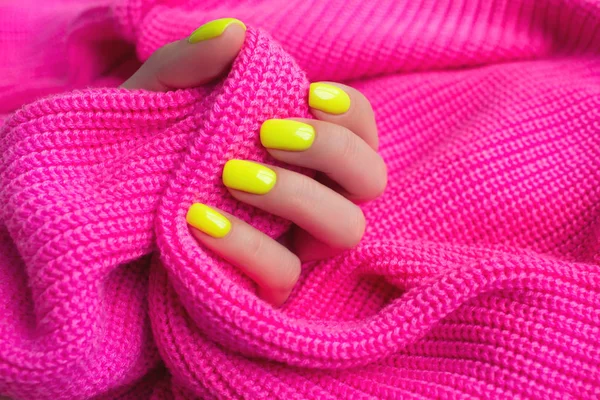 Elegante manicura femenina de moda. Neón uñas amarillas sobre fondo rosa plástico . — Foto de Stock