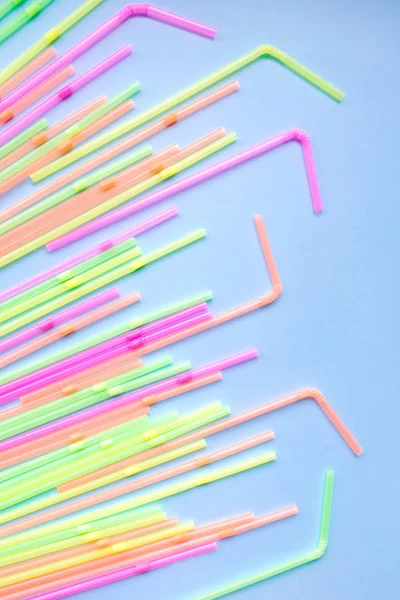 Colourful plastic straws on blue background. Cocktail tubes.