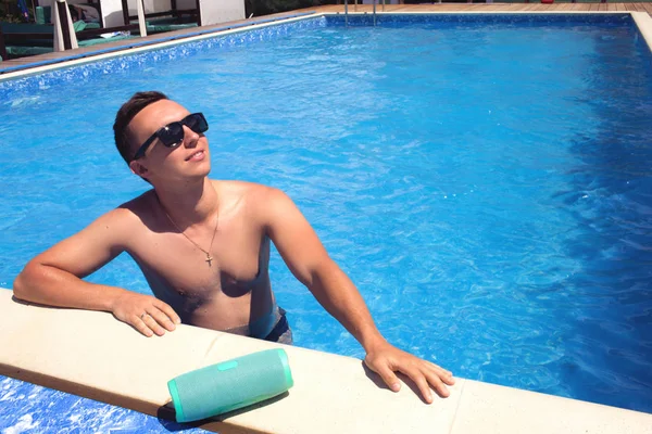 戴着太阳镜的迷人年轻人在游泳池里发冷. — 图库照片
