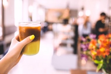 Bulanık arka plan kafede elinde soğuk kahve fincanı.