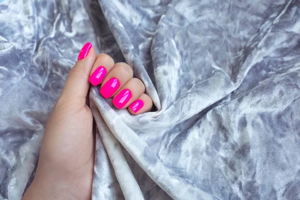 Elegante manicura femenina de moda. Neón plástico uñas de color rosa sobre un fondo gris texturizado . — Foto de Stock