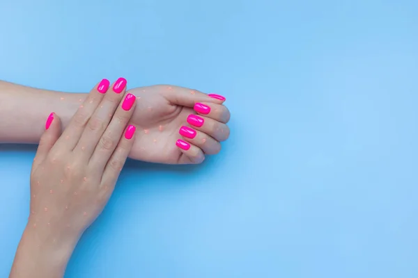 Elegante manicura femenina de moda. Hermosas uñas de plástico de neón rosa sobre fondo azul . — Foto de Stock