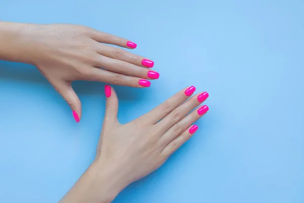 Elegante manicura femenina de moda. Hermosas uñas de plástico de neón rosa sobre fondo azul . — Foto de Stock