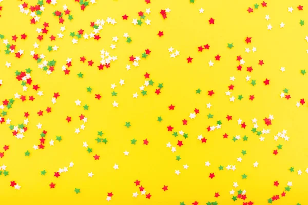 Coloridas estrellas festivas espolvorean como un marco sobre fondo amarillo . —  Fotos de Stock