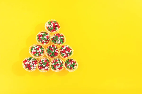 Espolvoreos coloridos sobre un fondo amarillo formando una forma de árbol de Navidad . — Foto de Stock