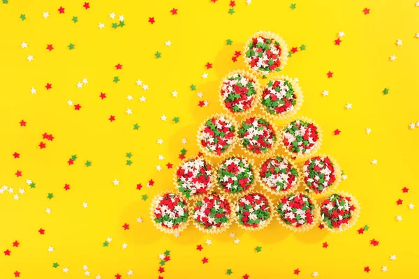 Красочные брызги на желтом фоне, создающие форму рождественской елки . — стоковое фото