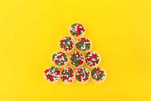 Espolvoreos coloridos sobre un fondo amarillo formando una forma de árbol de Navidad . — Foto de Stock