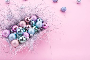 Noel kompozisyonu. Noel baloları, pembe ve mavi süslemeler pembe arka planda. Noel toplarıyla birlikte Noel hediyesi kutusu. Düz konum, kopyalama alanı, üst görünüm. Kış tatili, yeni yıl. Mutlu noel kartları. Metin için boşluk.