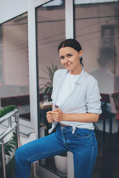 Sıradan tarzda gülümseyen güzel bir kız. Sevimli ve modaya uygun kıyafetler giyiyor. Şehir tarzı.