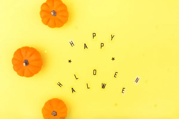 Happy Halloween letters on a yellow background with orange pumpkins Flat lay, copy space, top view. Happy Halloween Card.