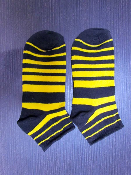 Striped baby socks, in black and yellow stripes, lie on a purple table