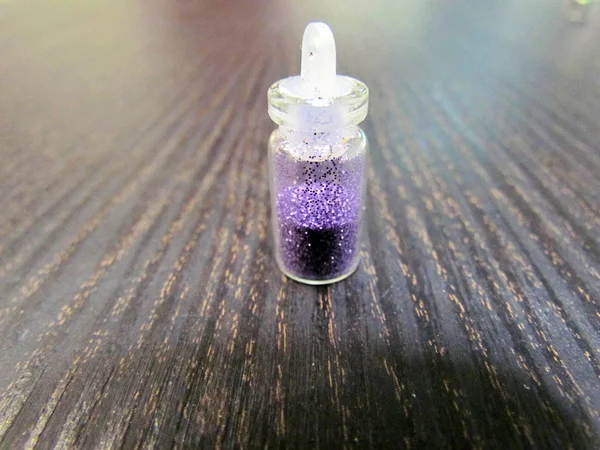 A small bottle with a decorative material for nail design, bright color