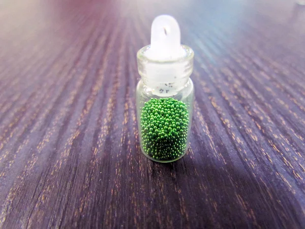 A small bottle with a decorative material for nail design, bright color