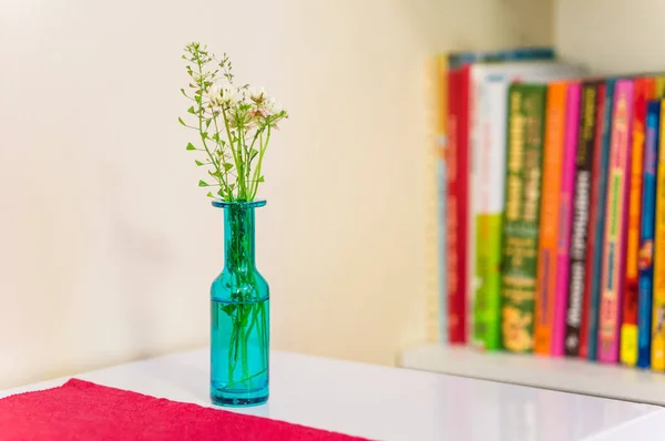 Бирюзовая голубая ваза с разноцветными книгами на заднем плане — стоковое фото