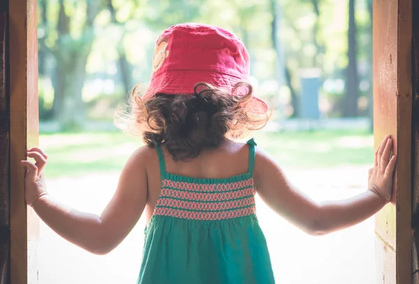 Menina pequena em chapéu vermelho em pé na porta . — Fotografia de Stock