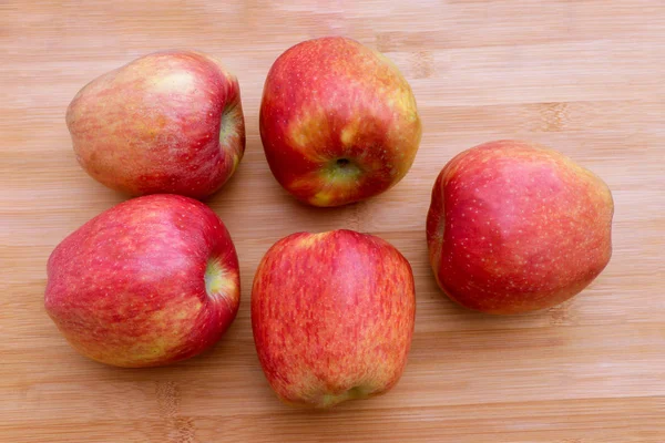 Group of five red apples placed on wooden surface
