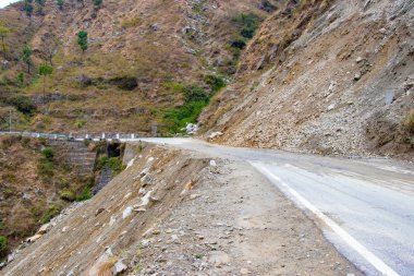 Toprak kaymaları ve kıvılcımlarla dağlarda yolda. Kayalar yolu kapatıyor