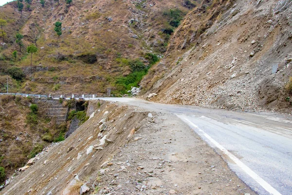 Toprak kaymaları ve kıvılcımlarla dağlarda yolda. Kayalar yolu kapatıyor