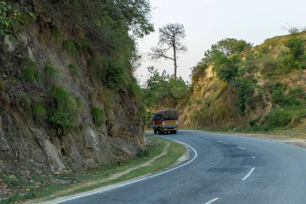 Ciężarówka toczenia na zakrzywionej drogi lub autostrady w obszarze wzgórza. — Zdjęcie stockowe