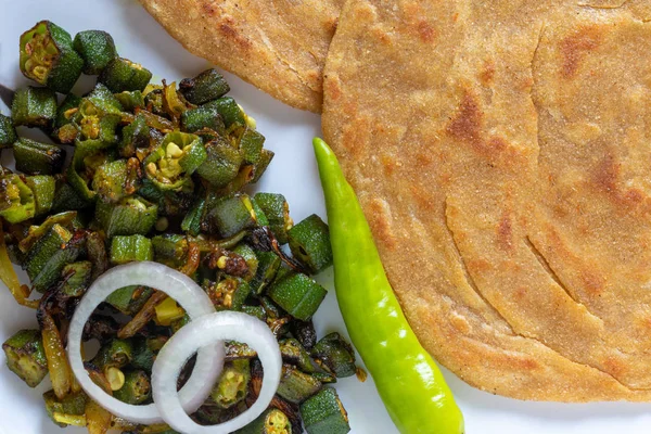 Lachha Paratha, pan plano en capas de trigo integral con sabzi Masala Bhindi (dedo de la dama) o Bhaji o receta . Imagen De Stock