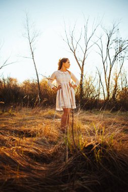 Gün batımı bir arka plan üzerinde bir alanda güzel kız.