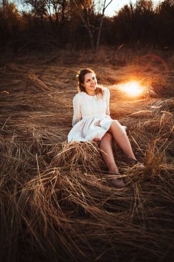 Kız günbatımı arka plan alanında oturuyor.