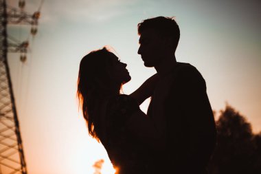 Bir adam ve kız bir gün batımı arka plan alanda siluetleri.
