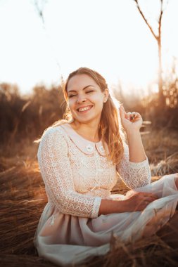 Kız günbatımı arka plan alanında oturuyor.