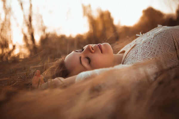 Girl lying on the field on a sunset background.