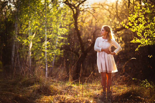 Beautiful girl standing in a field on a sunset background.