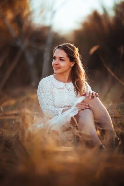 Kız günbatımı arka plan alanında oturuyor.