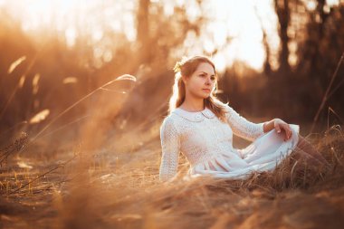 Kız günbatımı arka plan alanında oturuyor.