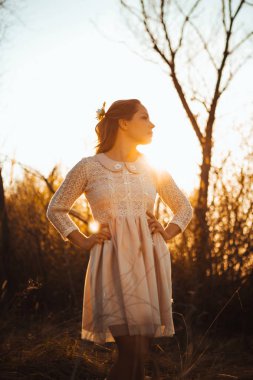 Gün batımı bir arka plan üzerinde bir alanda güzel kız.