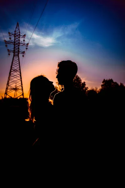男と女を夕日を背景にフィールドでのシルエット — ストック写真