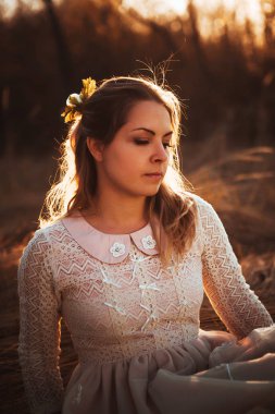 Kız günbatımı arka plan alanında oturuyor.