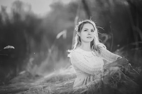 黑白照片的女孩坐在田野上的日落背景 — 图库照片