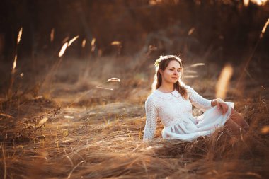 Kız günbatımı arka plan alanında oturuyor.