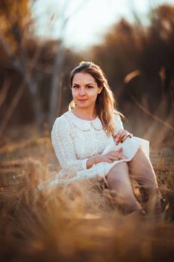 Kız günbatımı arka plan alanında oturuyor.