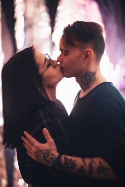 Erkekler ve kızlar arka planda öpüşürler.